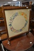 A vintage oak framed fire screen having embroidered panel