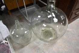 A vintage glass carboy and a similar bottle