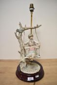 A mid-20th Century Capodimonte porcelain lamp, modelled as two children on a swing and measuring
