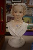 A moulded pottery bust of a young boy, head and shoulders, lightly accented and with painted