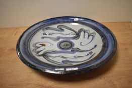 A large abstract studio pottery charger, having hand painted blue and green motifs on a glaze