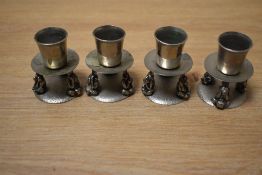 A set of four aluminium candle holders, the base supported by three Mizaru monkeys, h5cm.