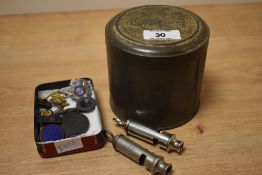 A lot comprising of a pair of early 20th century police whistles, a Cadbury's chocolate tin, h10.