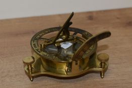 A reproduction brass sundial compass with three adjustable feet