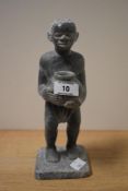 An African Soap Stone Carving of a tribal figure carrying a water jar, indistinctly signed to