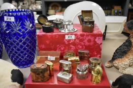 A collection of various inkwells in varied shapes and sizes, one in the form of a shell casing.