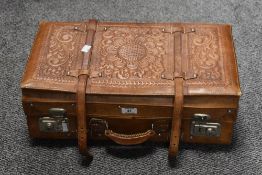 An early 20th century leather travel case, having embossed foliage decoration to the top, hammer and