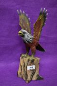 A decorative carved and painted wooden eagle figure, modelled standing with outstretched wings 32cm