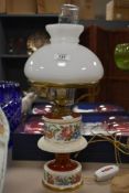 A mid-century opaque glass and ceramic oil lamp, decorated having hand coloured flowers and gilt