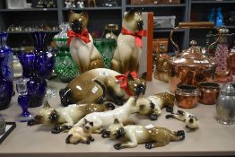 An assortment of cermaic Siamese cat studies in varied stances and sizes, the tallest measuring 37cm