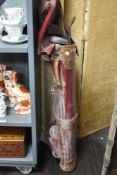A vintage leather golf bag containing various clubs, to include drivers, hickey shafted clubs,