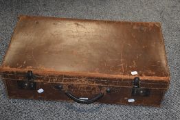 An early 20th century leather suitecase having genuine cowhide and brass fixtures, L64cm.