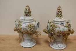 A pair of porcelain twin handled lidded baluster vase's, extravagantly decorated in high relief with