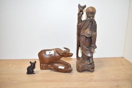 A 20th century carved Chinese rosewood figure of a bearded immortal clutching his staff and bag,