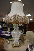 A large vintage cut crystal baluster table top lamp, having cream colour silk shade, standing on a