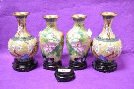 A group of four Chinese Cloisonne enamel baluster vases sitting on wooden stands, decorated having