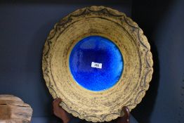 A large earthern ware plate, the centre having a sea blue glaze boarded by a Aztec style pattern,