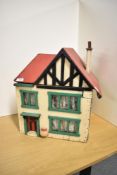 A vintage two storey wooden Dolls House having a small amount of furniture inside, height 45cm