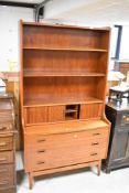 A vintage teak bureau bookshelf having pull out flap , with tambour concealed stationery