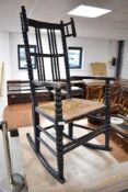 A Victorian dark stained rocking chair having bobbin turned frame and rush seat