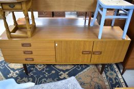 A vintage teak effect sideboard having stylised recessed handles, width approx 176cm