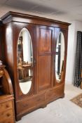 An early 20th century inlaid mahogany mirror door wardrobe, with moulded and inlaid cornice over the