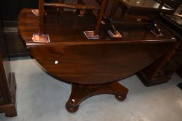 A William IV mahogany drop leaf dining table on typical platform base with bun feet