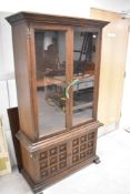 A mid to late 20th Century oak bookcase having glazed top with lower cupboard having cushion