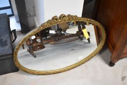 A traditional gilt frame wall mirror of oval form, approx. 72 x 47cm, with swag and bow decoration