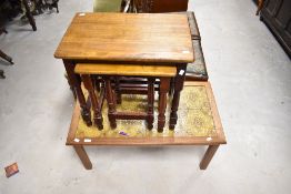 A vintage teak and tile top coffee table and a stained frame nest of three tables