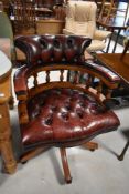A traditional captains chair having red leather buttoned upholstery