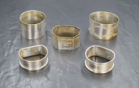 A group of five silver napkin rings, of various size and design including engraved decoration and