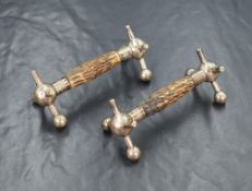 A pair of white metal and antler knife rests, of traditional form having central antler bars, raised