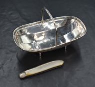 A late Edwardian silver trinket tray, in the form of a basket tray, raised on two bar legs, marks