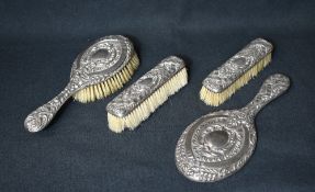 A late Victorian/Edwardian silver mounted vanity set, comprising hair brush, a mirror and two