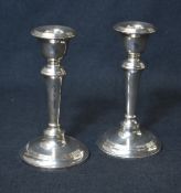 A pair of late Edwardian silver candlesticks, having circular sconces with step moulding, on knopped