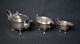 A late Edwardian silver three piece tea set, comprising a tea pot, sugar and cream each of oval form