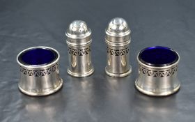 A set of four George V silver condiments, having pierced decoration and blue glass liners, marks for