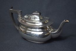 A George V silver teapot, of bulbous oval form with curved spout opposed by an angular handle,