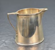 A George V silver cream jug, of oval form having a step moulded rim, canted ends and raised on a