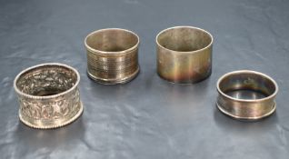 A group of four silver and white metal napkin rings, including an engine turned example and an