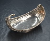 A George V silver bowl, of long boat form having egg and dart rim and curved scroll handles, with
