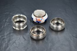 A pair of late Edwardian silver napkin rings, having engraved floral decoration with vacant circular