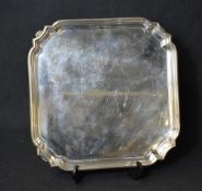 An Elizabeth II silver salver, of square form with a moulded rim, raised on four scroll feet,