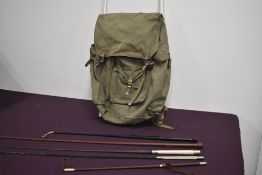 A green canvas frame rucksack containing five leather riding crops