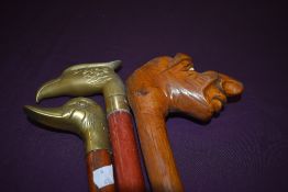 Three walking sticks, two with brass heads, one of an eagle the other of a duck and one with a