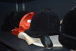 Five riding hats in varying sizes and a back protector one hat marked harry hall