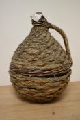 A late 19th / early 20th century wine carboy with corked top, dressed in a rattan and wicker jacket,