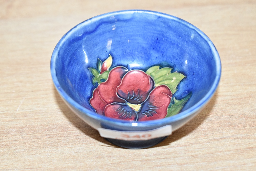 A small attractive Moorcroft pottery bowl, decorated with poppy on a blue glaze ground, pattern No.