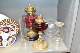 A late 19th / early 20th century brass and cranberry glass oil lamp, decorated in the Art Nouveau